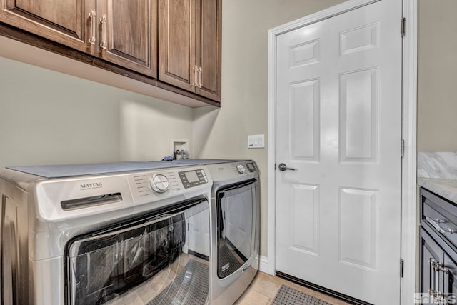 clothes washing area with cabinets, independent washer and dryer, and light tile patterned floors