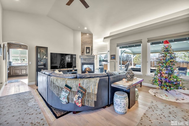 living room featuring a multi sided fireplace, ceiling fan, light hardwood / wood-style flooring, and lofted ceiling