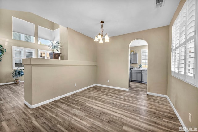 unfurnished dining area with wood-type flooring and an inviting chandelier