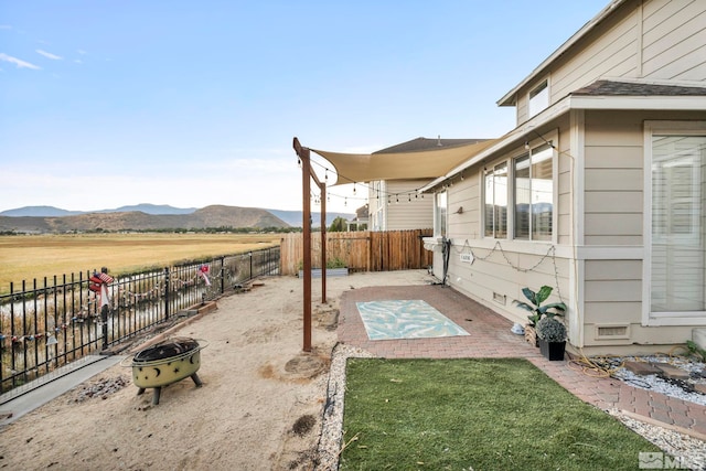 view of yard featuring a mountain view, a patio, a rural view, and an outdoor fire pit