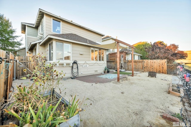 rear view of property featuring a patio and an outdoor fire pit