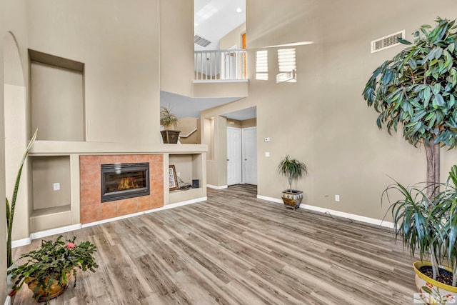 living room featuring hardwood / wood-style floors, built in shelves, a fireplace, and high vaulted ceiling