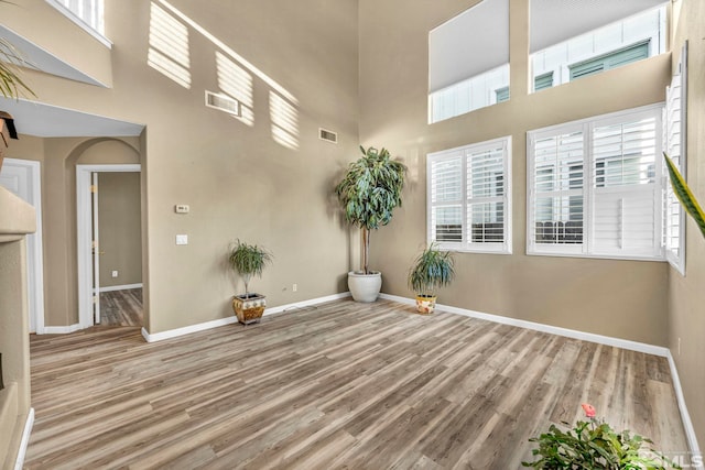 spare room with hardwood / wood-style floors and a towering ceiling