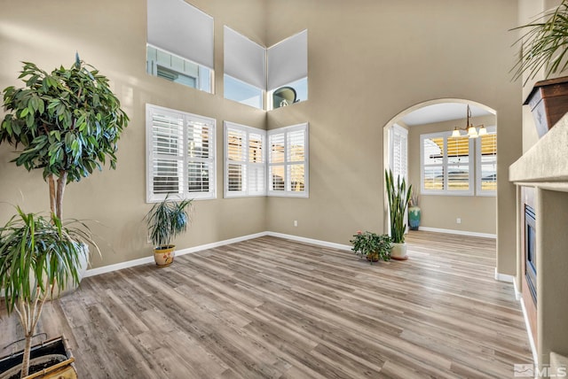 unfurnished living room featuring a high ceiling, light wood-type flooring, and an inviting chandelier