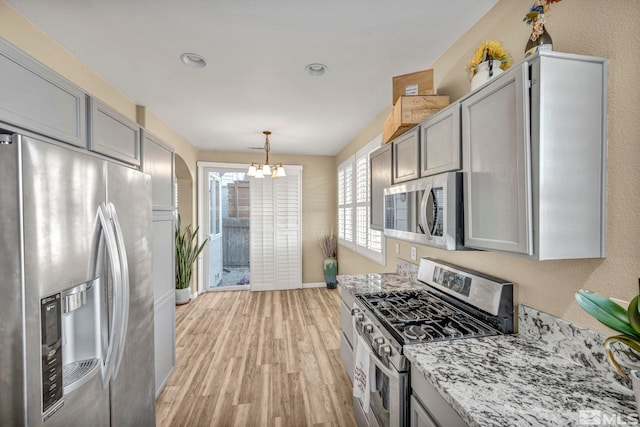 kitchen with a chandelier, stainless steel appliances, light hardwood / wood-style flooring, and gray cabinetry