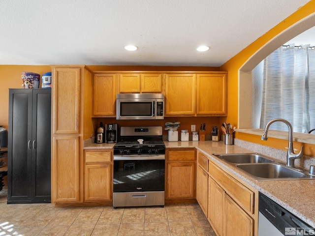 kitchen featuring light tile patterned flooring, appliances with stainless steel finishes, a textured ceiling, and sink