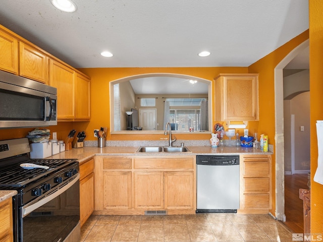 kitchen featuring appliances with stainless steel finishes, a textured ceiling, sink, light brown cabinets, and light tile patterned floors