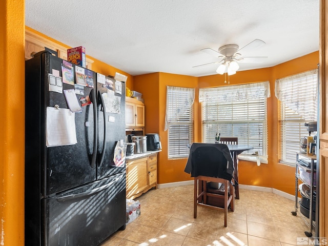 kitchen with black refrigerator, a textured ceiling, ceiling fan, light tile patterned floors, and light brown cabinets