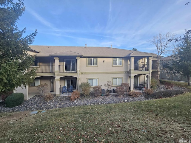 back of house with a balcony and a lawn