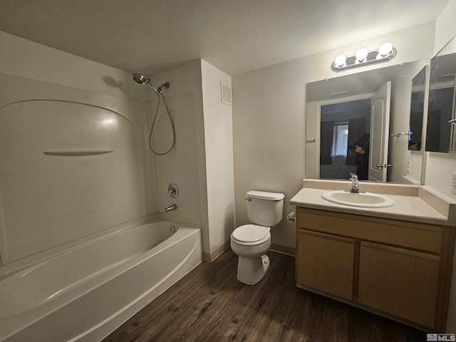 full bathroom with hardwood / wood-style floors, a textured ceiling, toilet, vanity, and bathtub / shower combination