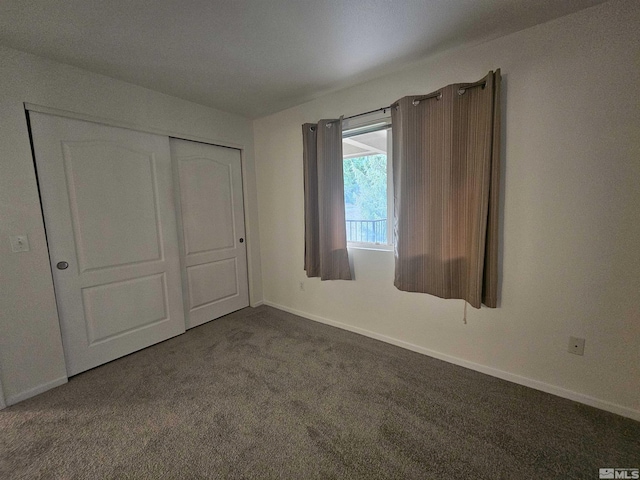 unfurnished bedroom with a closet and dark colored carpet