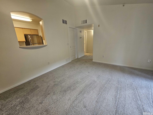 carpeted empty room featuring a towering ceiling