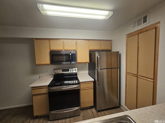 kitchen with light brown cabinetry, stainless steel appliances, and dark hardwood / wood-style floors