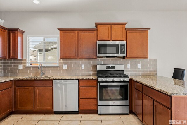 kitchen featuring light stone countertops, sink, light tile patterned flooring, and stainless steel appliances