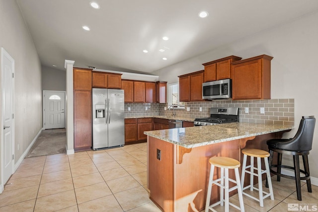 kitchen with light stone countertops, a kitchen breakfast bar, stainless steel appliances, and lofted ceiling