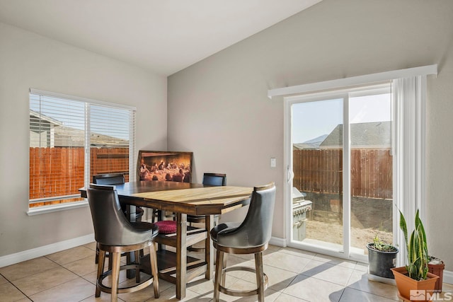 dining room featuring light tile patterned floors, a healthy amount of sunlight, and vaulted ceiling