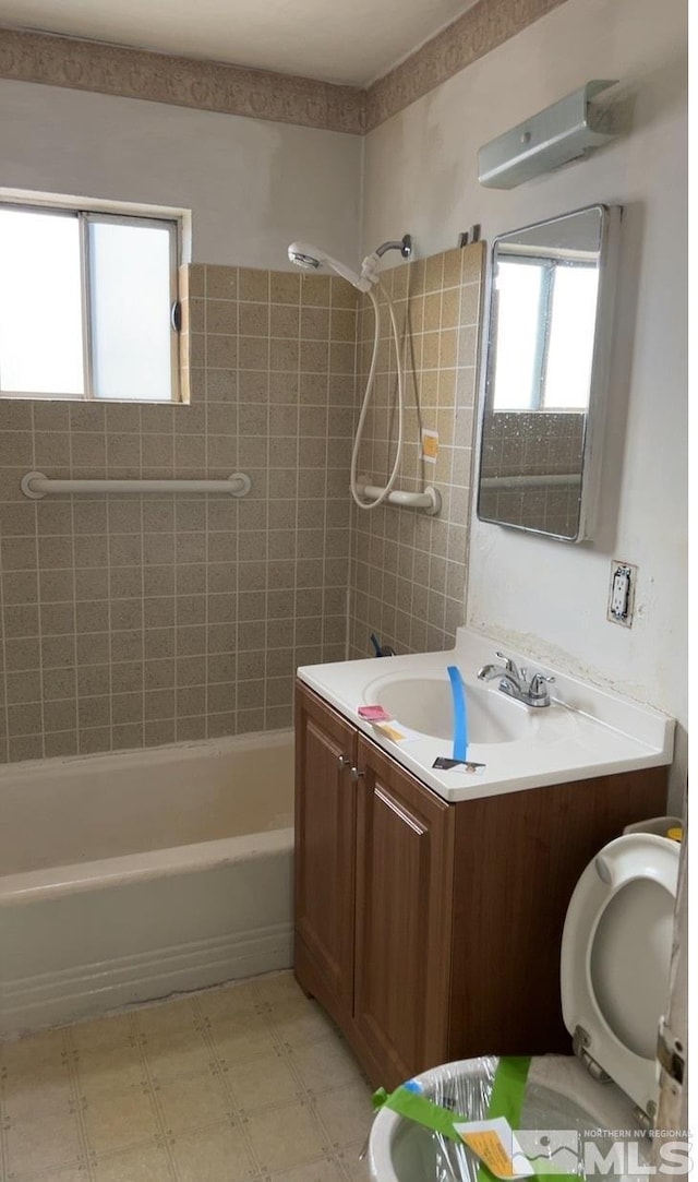 bathroom featuring a wealth of natural light, vanity, and tiled shower / bath combo