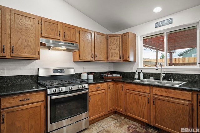 kitchen with dark stone countertops, sink, lofted ceiling, and stainless steel gas range