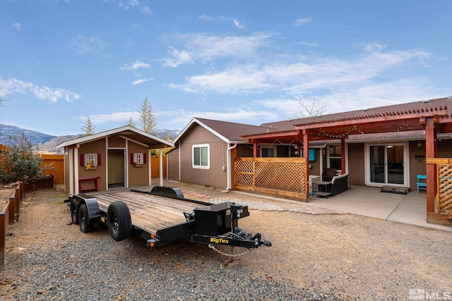 rear view of house with a mountain view, a storage shed, and a pergola