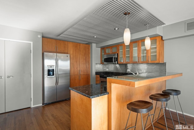 kitchen with kitchen peninsula, dark hardwood / wood-style flooring, stainless steel appliances, and a breakfast bar area