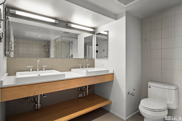 bathroom featuring a tile shower, tile patterned floors, tile walls, and sink