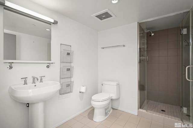 bathroom featuring tile patterned flooring, toilet, and a shower with door