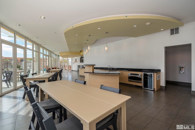 dining space with dark tile patterned flooring, floor to ceiling windows, sink, and beverage cooler