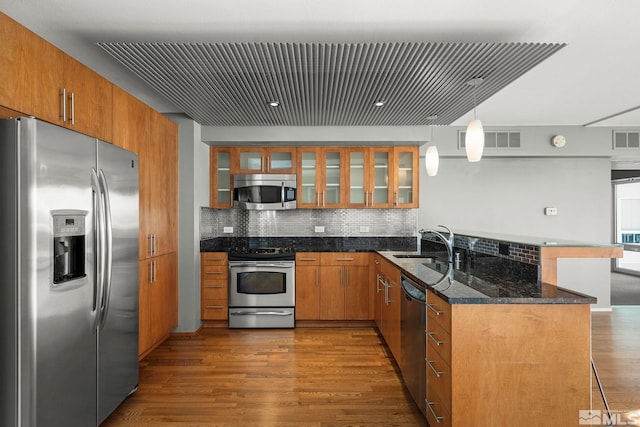 kitchen featuring pendant lighting, sink, dark hardwood / wood-style floors, appliances with stainless steel finishes, and kitchen peninsula