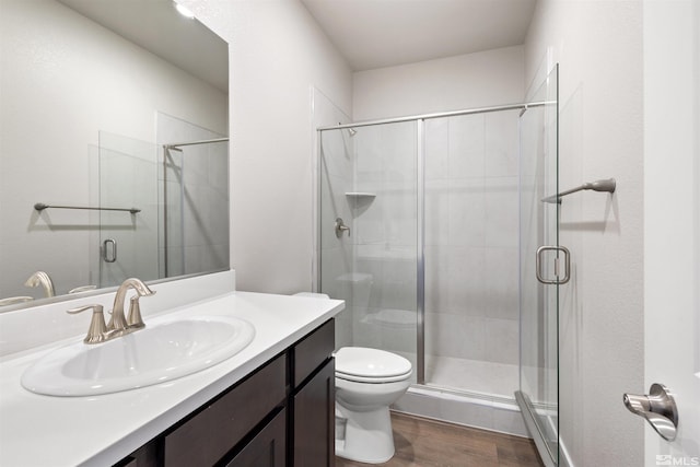 bathroom featuring wood-type flooring, vanity, toilet, and an enclosed shower