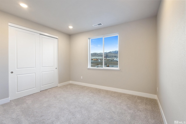 unfurnished bedroom featuring light carpet and a closet