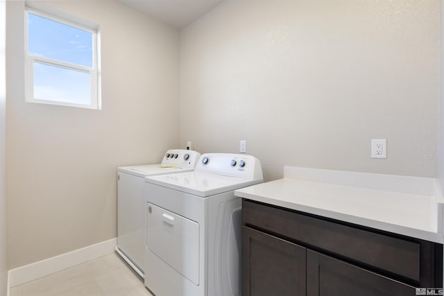 laundry area with cabinets, light tile patterned flooring, and washing machine and clothes dryer