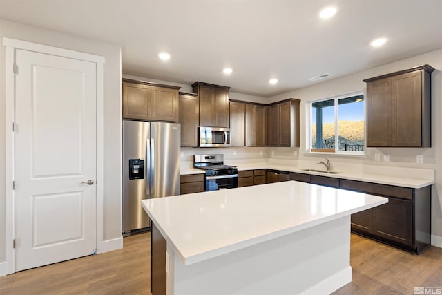 kitchen with a center island, sink, light hardwood / wood-style flooring, dark brown cabinets, and stainless steel appliances