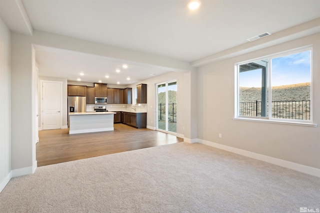 kitchen featuring a wealth of natural light, a kitchen island, light hardwood / wood-style floors, and appliances with stainless steel finishes