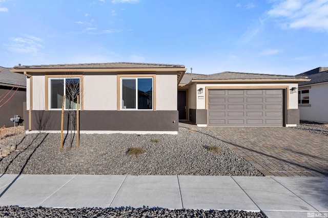 view of front of home featuring decorative driveway, an attached garage, and stucco siding