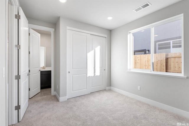 unfurnished bedroom with recessed lighting, a closet, visible vents, light carpet, and baseboards