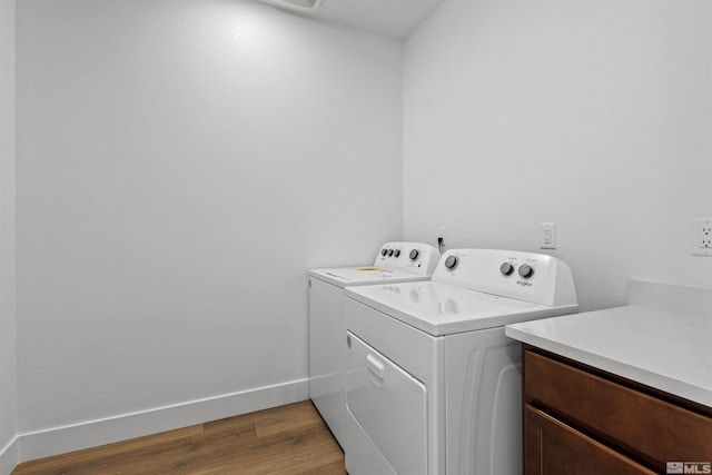 clothes washing area featuring washing machine and dryer, baseboards, and wood finished floors