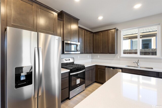 kitchen with appliances with stainless steel finishes, light countertops, and a sink