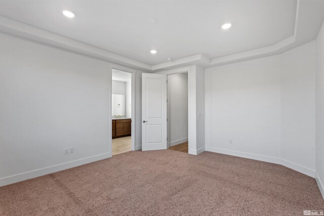 unfurnished room featuring baseboards, recessed lighting, a raised ceiling, and light colored carpet