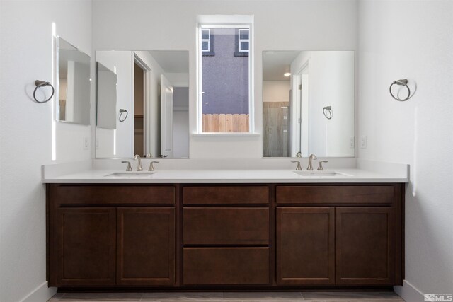 full bathroom with double vanity, baseboards, and a sink