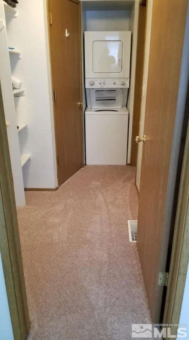 laundry area with light carpet and stacked washer and dryer