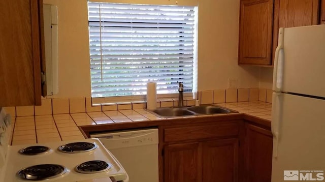 kitchen featuring tile counters, white appliances, and sink