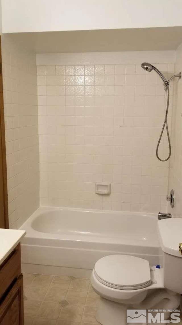 full bathroom with tile patterned flooring, vanity, tiled shower / bath combo, and toilet