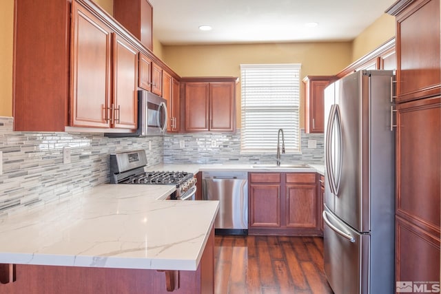 kitchen with sink, stainless steel appliances, dark hardwood / wood-style flooring, kitchen peninsula, and a kitchen bar