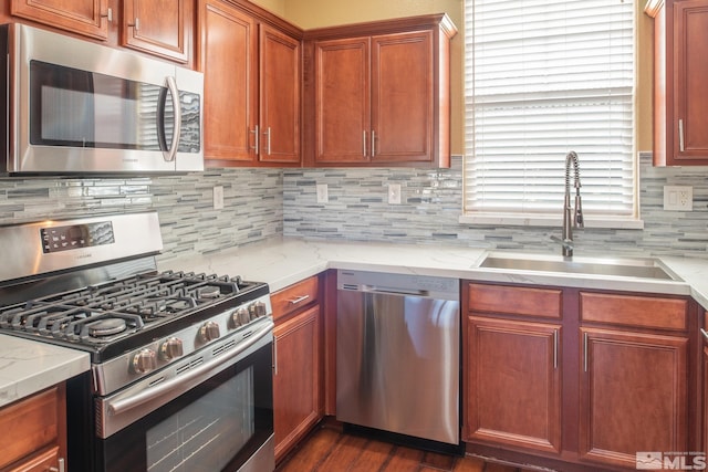 kitchen with sink, light stone counters, dark hardwood / wood-style flooring, decorative backsplash, and appliances with stainless steel finishes