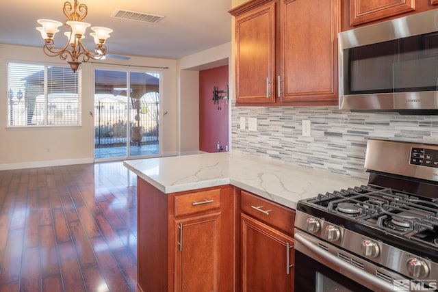 kitchen featuring backsplash, light stone counters, dark wood-type flooring, and appliances with stainless steel finishes