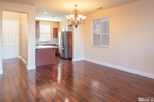 kitchen with decorative backsplash, decorative light fixtures, stainless steel refrigerator, and dark wood-type flooring