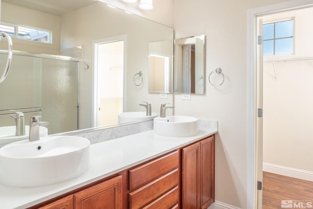 bathroom featuring a wealth of natural light, hardwood / wood-style floors, vanity, and a shower with shower door