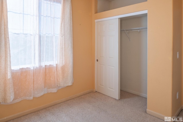 unfurnished bedroom with light colored carpet and a closet