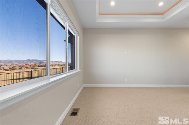 carpeted spare room with a mountain view, crown molding, and a tray ceiling