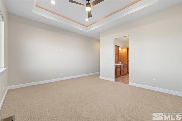 carpeted spare room with a raised ceiling, ceiling fan, and ornamental molding